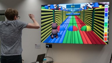 Photograph of someone playing the game Run Grizzly Bear, made for the jam. The game is an endless runner that you play by running on special copper pads on the floor, jumping between lanes as the game requires. The player is captured mid jump.